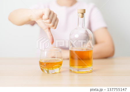 woman show thumb down hand gesture to refuse a glass of whisky, Healthy man say no to alcohol drink, stop alcoholism and addiction concept. Responsible man reject a drink before driving and quit booze woman show thumb down hand gesture to refuse a glass of whisky, Healthy man say no to alcohol drink, stop alcoholism and addiction concept. Responsible man reject a drink before driving and quit booze 137755147
