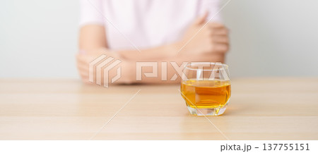 woman with glass of whiskey on table, suffering from alcohol addiction and alcoholism concept. depicting emotional distress, depression, substance abuse problem, unhealthy lifestyle and mental health 137755151