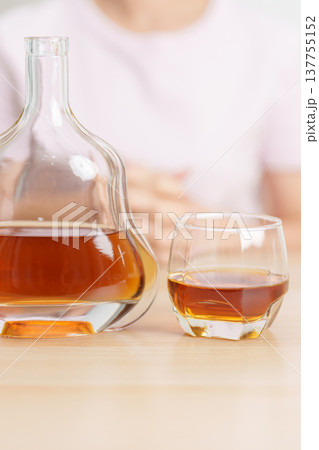 woman with glass of cognac on table, suffering from alcohol addiction and alcoholism concept. depicting emotional distress, depression, substance abuse problem, unhealthy lifestyle and mental health 137755152