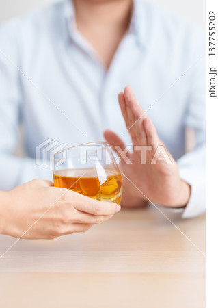 Man making stop hand gesture to refuse a glass of whiskey, Healthy man say no to alcohol drink, stop alcoholism and addiction concept. Responsible man reject a drink before driving and quit booze Man making stop hand gesture to refuse a glass of whiskey, Healthy man say no to alcohol drink, stop alcoholism and addiction concept. Responsible man reject a drink before driving and quit booze 137755202