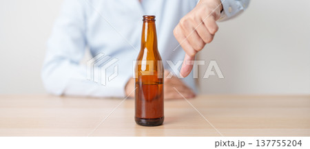 man show thumb down hand gesture to refuse a bottle of Beer, Healthy man say no to alcohol drink, stop alcoholism and addiction concept. Responsible man reject a drink before driving and quit booze 137755204
