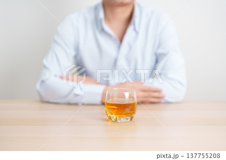 man with glass of whiskey on table, suffering from alcohol addiction and alcoholism concept. depicting emotional distress, depression, substance abuse problem, unhealthy lifestyle and mental health 137755208