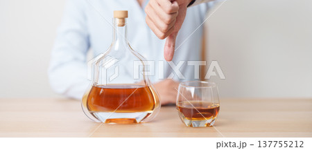 Man making thumb down hand gesture to refuse a glass of Cognac, Healthy man say no to alcohol drink, stop alcoholism and addiction concept. Responsible man reject a drink before driving and quit booze Man making thumb down hand gesture to refuse a glass of Cognac, Healthy man say no to alcohol drink, stop alcoholism and addiction concept. Responsible man reject a drink before driving and quit booze 137755212