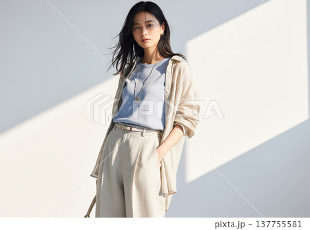 爽やかなブルーのインナーと羽織りで佇む凛とした表情の女性 137755581