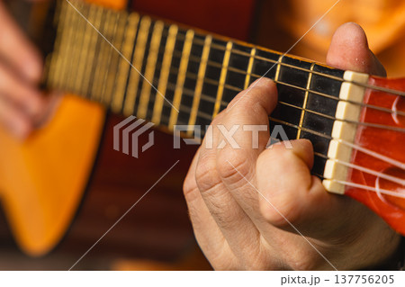 Man plays acoustic guitar indoors during evening Man plays acoustic guitar indoors during evening 137756205