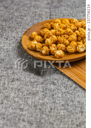 Bowl of popcorn placed on a wooden tray on a gray textured surface 137756214
