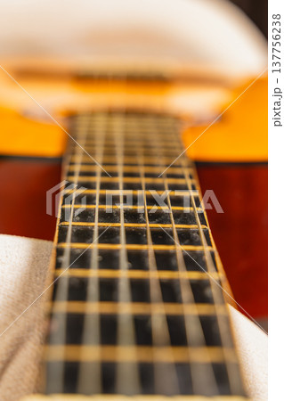 Guitar neck lies on a soft surface under natural light in a cozy setting Guitar neck lies on a soft surface under natural light in a cozy setting 137756238