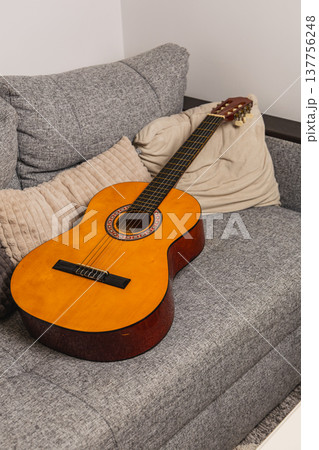 Guitar resting on a gray couch in a cozy indoor space Guitar resting on a gray couch in a cozy indoor space 137756248