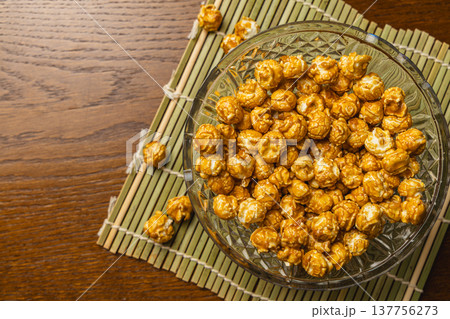 Bowl of popcorn on a wooden table with a bamboo mat underneath Bowl of popcorn on a wooden table with a bamboo mat underneath 137756273