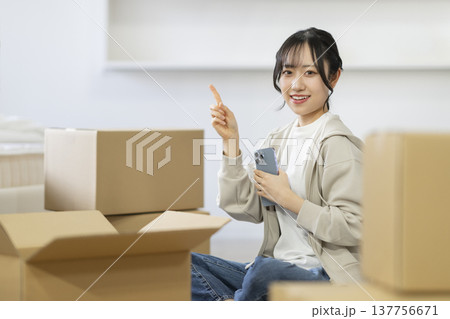 段ボール箱に囲まれて座る笑顔の若い女性　カメラ目線　引っ越し　イメージ 137756671