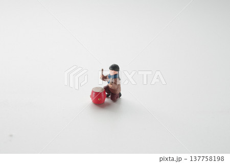 Miniature Figure Kneeling Beside Bright Red Festival Drum 137758198