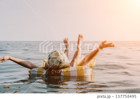 Float, Beach, Summer: Two people enjoy a sunny day on a float in the ocean. Float, Beach, Summer: Two people enjoy a sunny day on a float in the ocean. 137758495