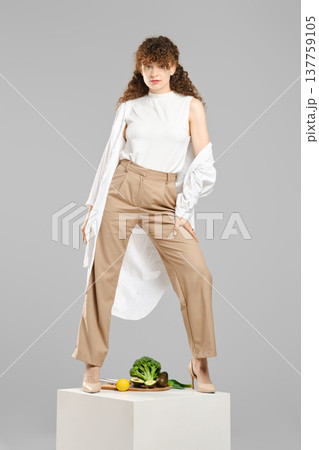 Woman posing on white cube with fresh vegetables 137759105