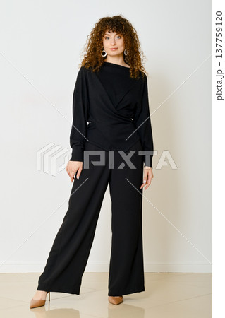 Stylish woman in black outfit poses in modern indoor setting during daylight hours Stylish woman in black outfit poses in modern indoor setting during daylight hours 137759120