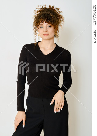 Model wearing black sweater poses against a plain wall showcasing spring fashion trends Model wearing black sweater poses against a plain wall showcasing spring fashion trends 137759129