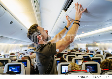 Passenger with diabetes placing carry on luggage in overhead compartment. 137759277