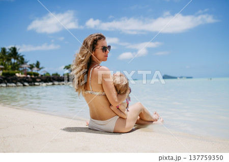 Mom breasfeeding little child on beach. 137759350