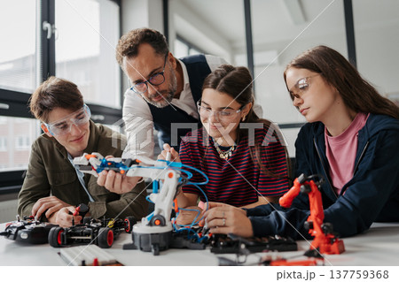 High school students working on robotics project with their teacher. 137759368