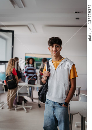 Confident teen student standing in modern classroom. 137759373