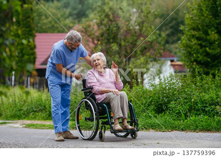 Senior patient and male nurse talking during walk outdoors. Senior patient and male nurse talking during walk outdoors. 137759396