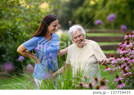 Home nurse spending time with elderly lady patient in garden. Home nurse spending time with elderly lady patient in garden. 137759435