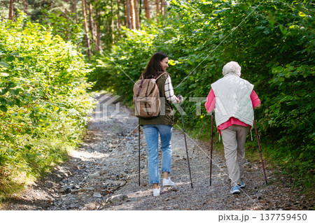Senior woman and daughter enjoying hike with trekking poles. Senior woman and daughter enjoying hike with trekking poles. 137759450