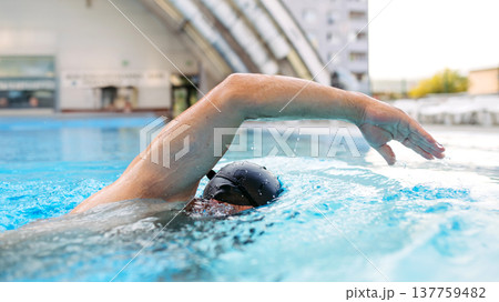 Focused swimmer performing crawl stroke in water. Focused swimmer performing crawl stroke in water. 137759482