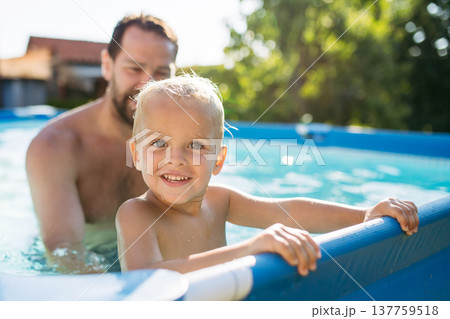 Father playing with little son in pool. Father playing with little son in pool. 137759518