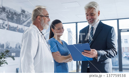 Medical sales representative presenting new medication to doctors, standing hospital hallway. 137759538