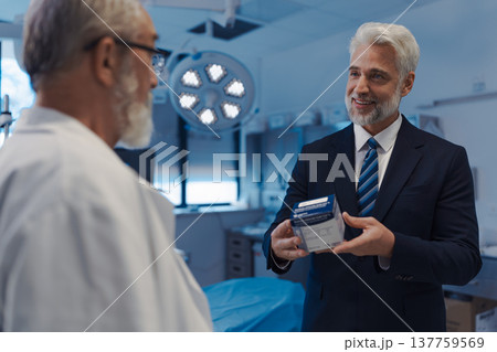 Medical sales representative presenting new medication to doctor, standing examination room. 137759569
