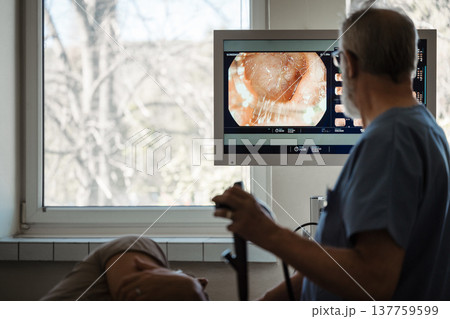 Doctor looking at monitior during gastroscopy procedure, examining upper digestive tract. 137759599