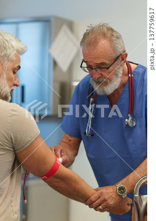 Older doctor drawing blood from patient's arm. 137759617