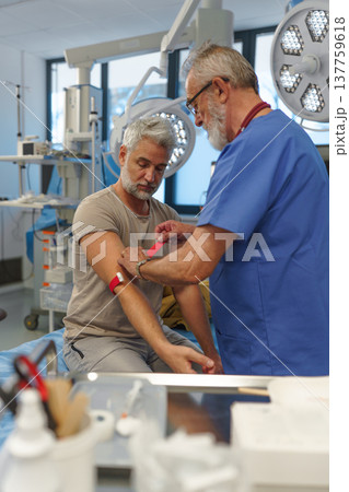 Older doctor drawing blood from patient's arm. Older doctor drawing blood from patient's arm. 137759618