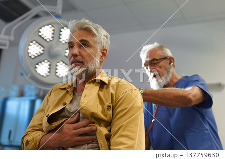 Doctor examining patient, listening to breathing with stethoscope. 137759630