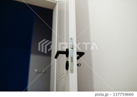 Installing door hardware and handle on interior door during home renovation. Installing door hardware and handle on interior door during home renovation. 137759660