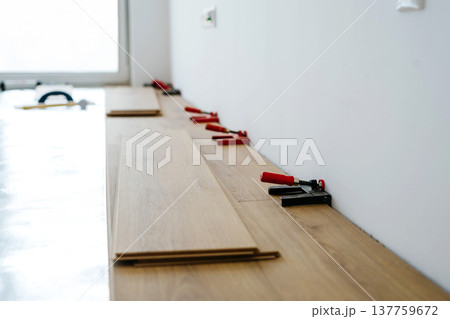 Installing laminate flooring with spacers during home renovation. Installing laminate flooring with spacers during home renovation. 137759672