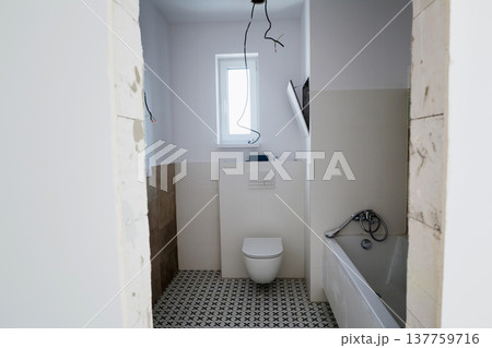 Bathroom renovation with toilet installation and unfinished electrical wiring. Bathroom renovation with toilet installation and unfinished electrical wiring. 137759716