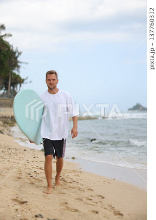 Casual Man With Surfboard Walking. Man In White Shirt Captures Natural Beachfront Lifestyle Image 137760312