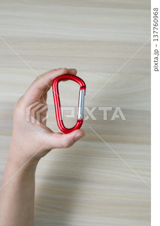 赤いカラビナを持つ手と木目調の背景（縦） 137760968