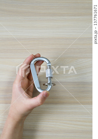 手に持ったシルバーのカラビナと広い余白 137761671