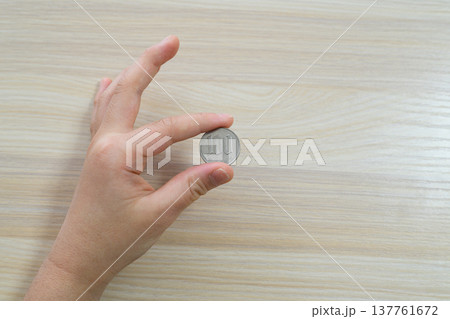 100円玉を指先でつまむ手元のアップ 137761672
