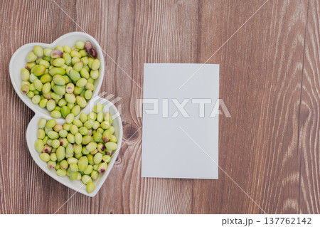Freshly harvested green olives in heart shaped plate on wooden table, Mediterranean superfood rich in vitamins with blank paper for copy space Freshly harvested green olives in heart shaped plate on wooden table, Mediterranean superfood rich in vitamins with blank paper for copy space 137762142