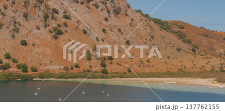 Drying mountain lake with wide strip of dried shore and orange rocky slope. 137762155