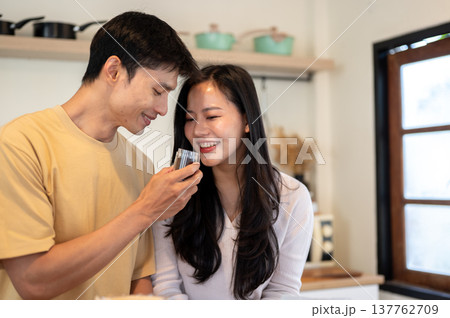 Asian man and woman couple smelling aroma from powder in grinder while making coffee in the kitchen. Asian man and woman couple smelling aroma from powder in grinder while making coffee in the kitchen. 137762709
