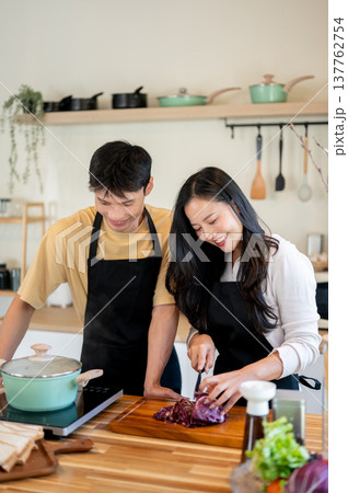 Asian couple woman girlfriend cutting vegetable as man boiling water cooking food at kitchen counter Asian couple woman girlfriend cutting vegetable as man boiling water cooking food at kitchen counter 137762754