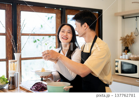 Asian couple a man boyfriend holding a woman girlfriend's hand over pasta plate at kitchen counter. Asian couple a man boyfriend holding a woman girlfriend's hand over pasta plate at kitchen counter. 137762781