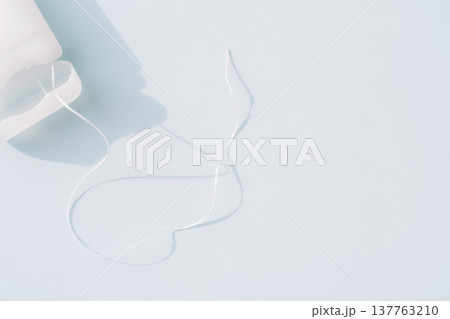 Dental floss strand from container on light blue background, minimal oral hygiene concept with copy space 137763210
