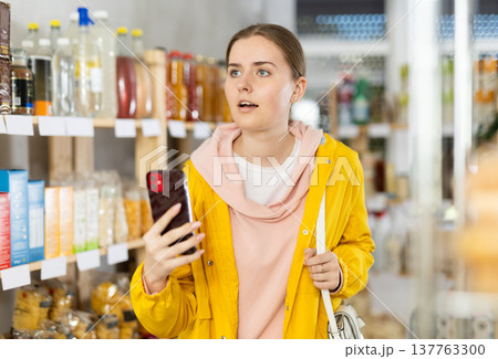 Girl scans QR code on products on supermarket shelves to check expiration dates Girl scans QR code on products on supermarket shelves to check expiration dates 137763300