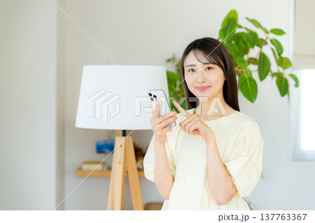部屋でスマホを操作する女性 137763367