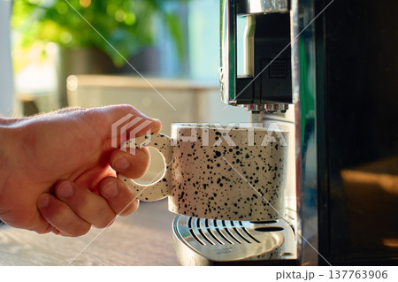 Person takes cup of freshly brewed coffee from coffee machine Person takes cup of freshly brewed coffee from coffee machine 137763906